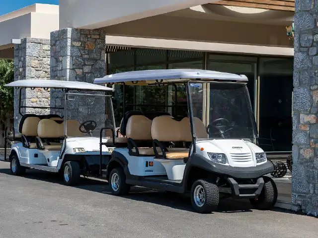 Golf Cart Lithium Battery Applications Two white golf carts parked at a building entrance, an application for lithium golf cart batteries